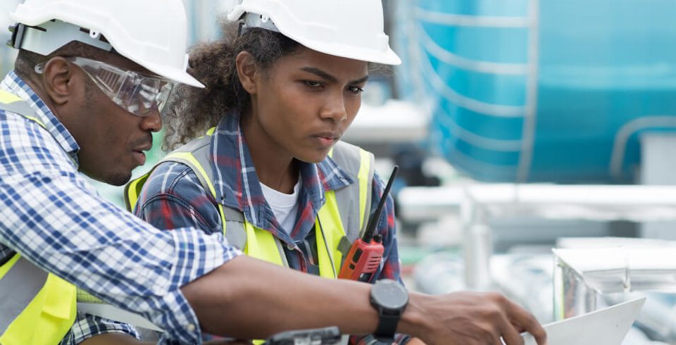 Young girl working with tutor both wearing hard hats