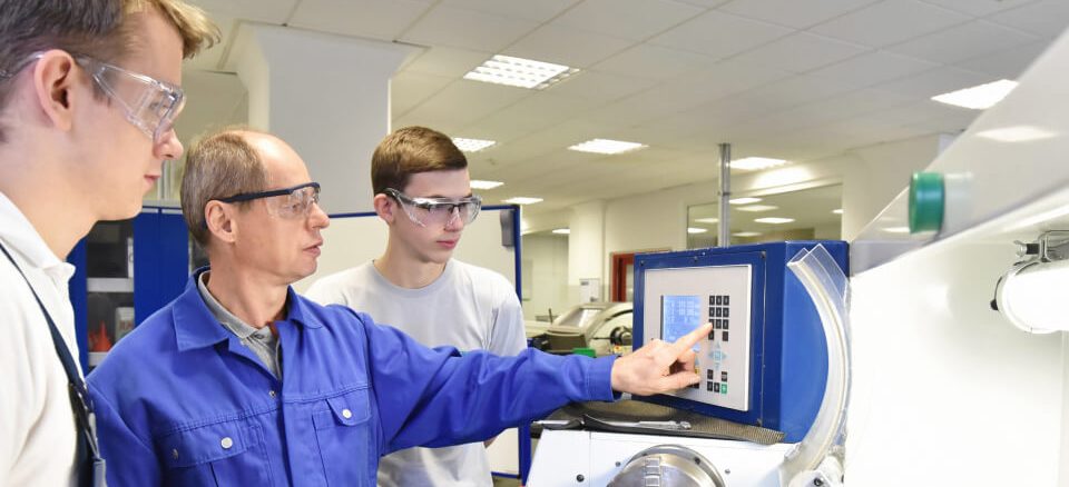 Man teaching two young men about engineering